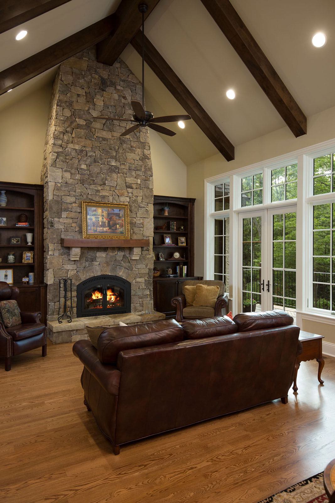 Tudor living room with stone hearth and fireplace and exposed rafters, custom built by Bluestone Construction.