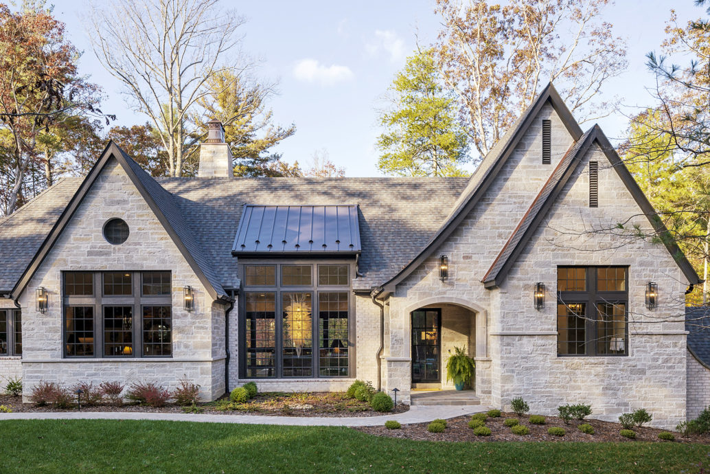 Luxury french contemporary home with light brick and stone exterior and dark roof.