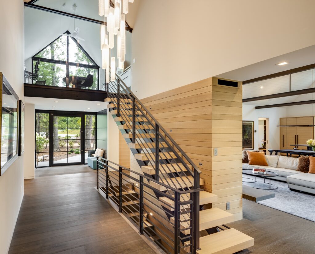 modern staircase with custom-made metal railings, warm wood flooring, and a statement chandelier in a luxury home