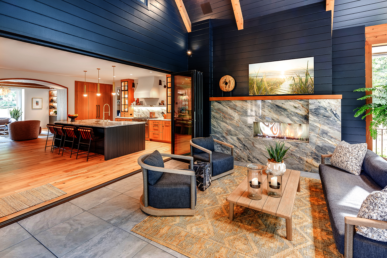 Luxury indoor-outdoor living space featuring a modern fireplace, open-concept kitchen, and seamless transition to an outdoor seating area in a high-end custom home built by luxury homebuilder Bluestone Construction