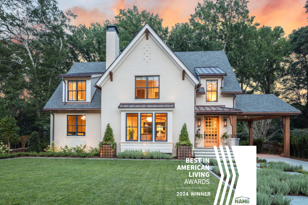 Award-winning modern farmhouse-style custom home with white painted brick exterior, large black-trimmed windows, and a landscaped front yard at sunset. Greenville South Carolina